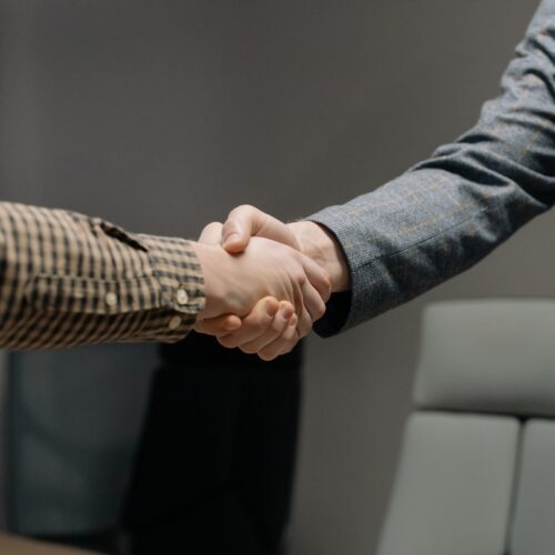 Two men are shaking hands. They are both in business attire.