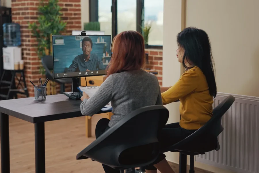 2 hiring team members interviewing a candidate on a video call at an office desk